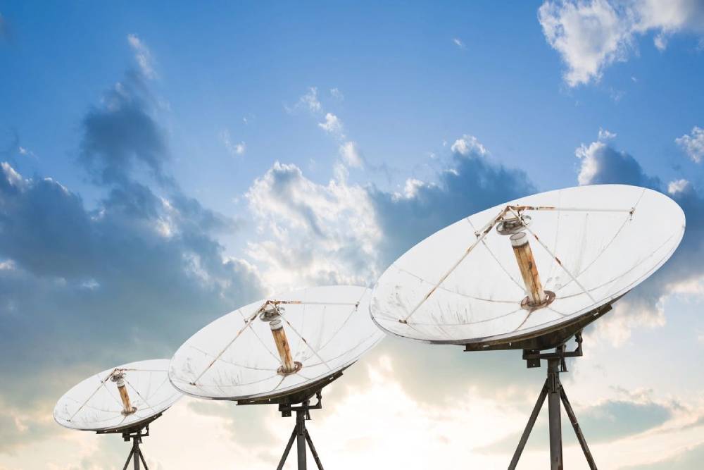 A group of satellite dishes sitting in the middle of a field.